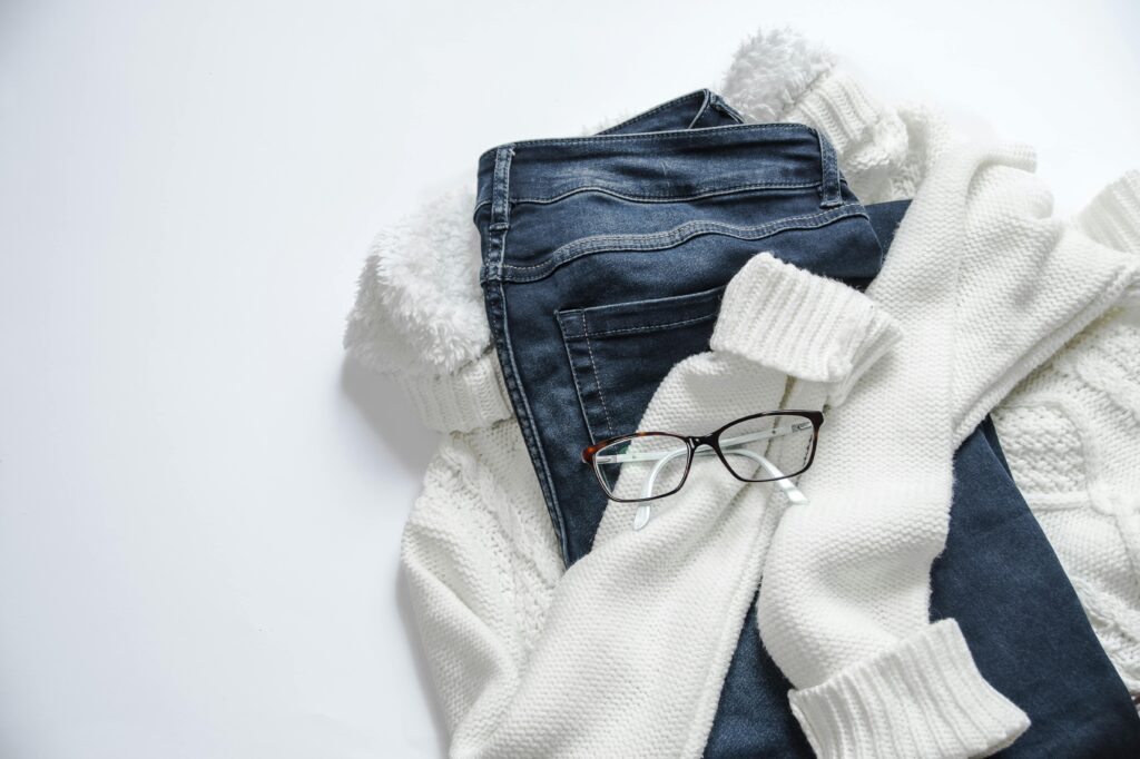 Which Company Is Best for Clothes? A Complete Guide for Shoppers Stylish flat lay featuring denim jeans, white sweater, and eyeglasses on a bright background.