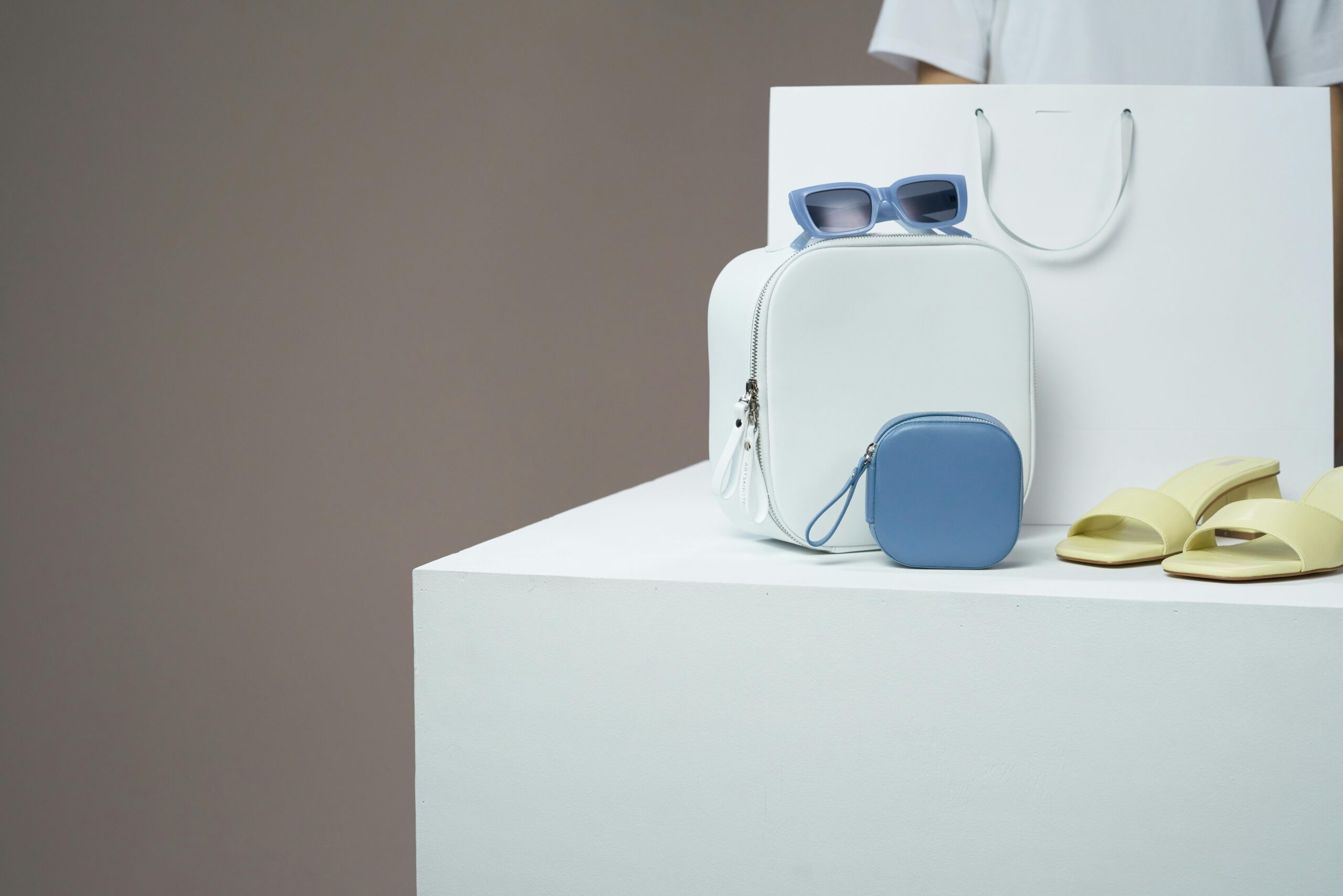 Modern fashion accessories including backpack, sunglasses, and sandals in minimalistic display.